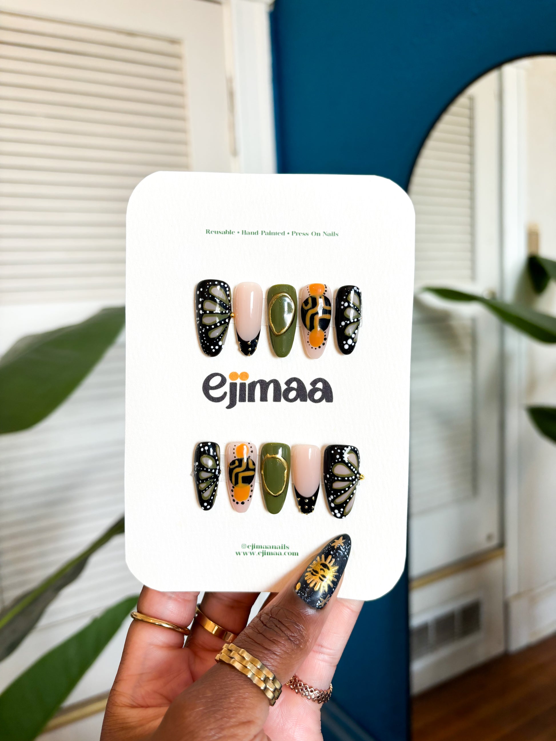 Card with butterfly nail art designs held by a hand, with 'ejimaa' branding.