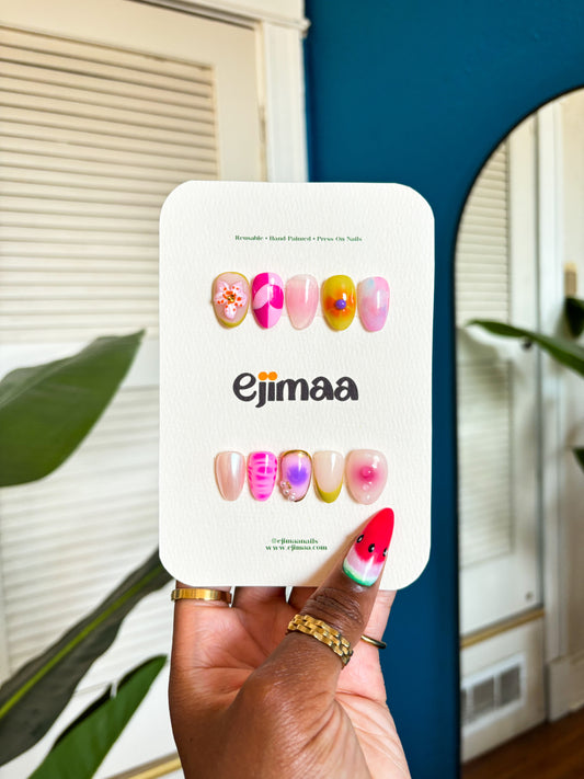 Hand holding a white card with colorful text and 'ejimaa' branding against a blue wall.