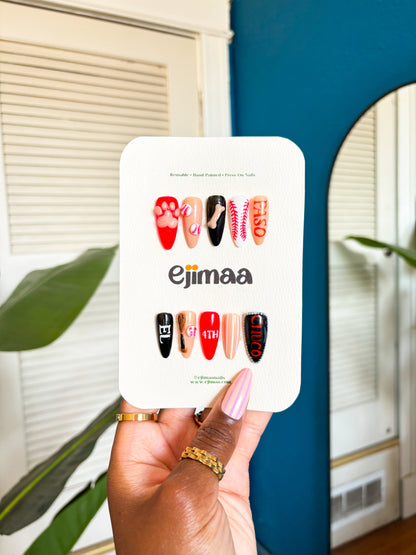 Hand holding a nail card with 'ejimaa' brand name against a blue wall. 
