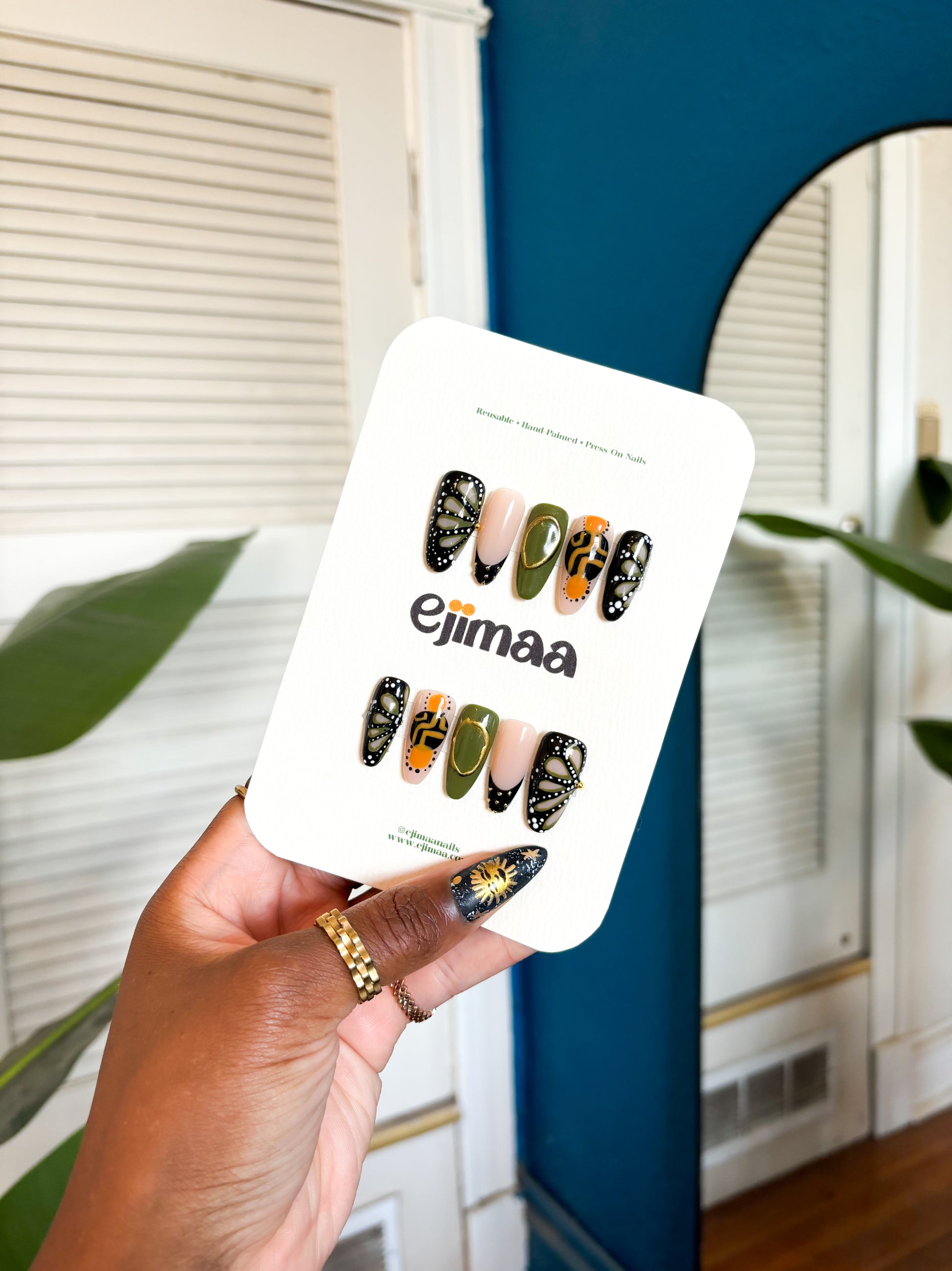 Hand holding a product packaging with colorful designs and text, against a neutral indoor background.